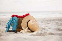 Kapelusz i klapki oparte o plecak na plaży